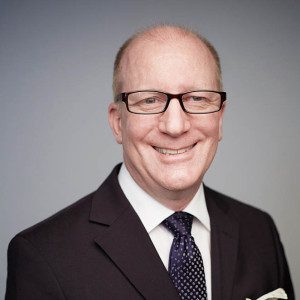 A man in a suit and tie smiling for the camera.