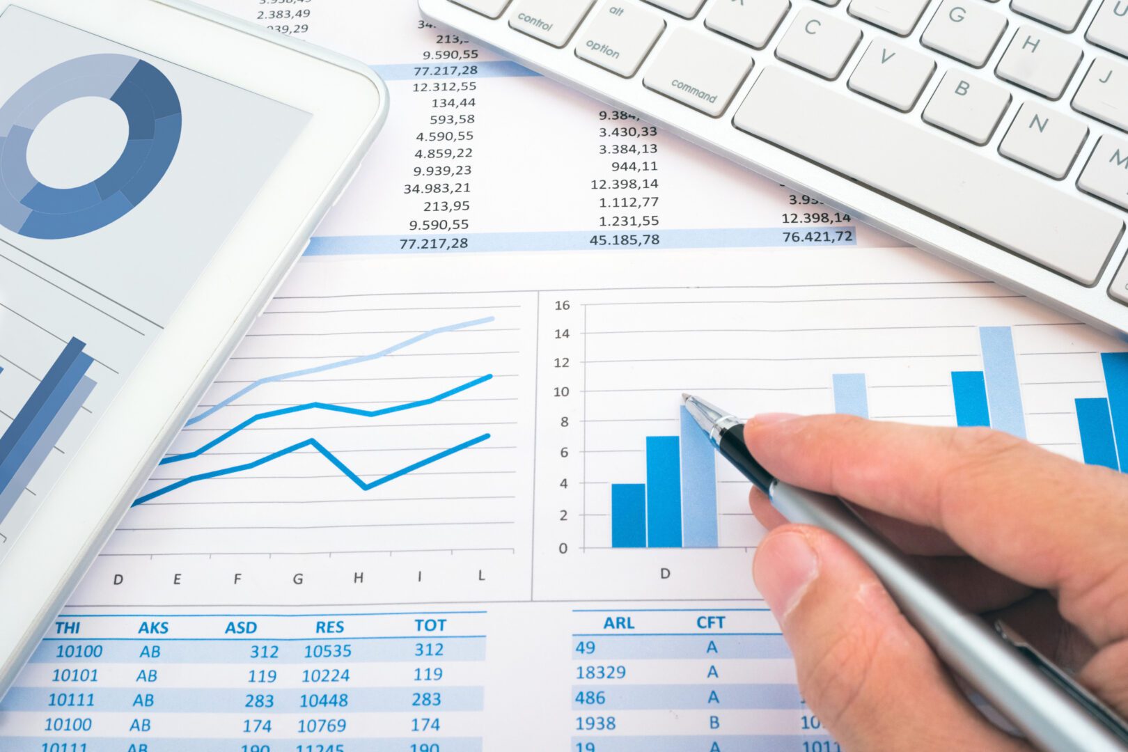 A person is using a pen to check the numbers on a financial report.