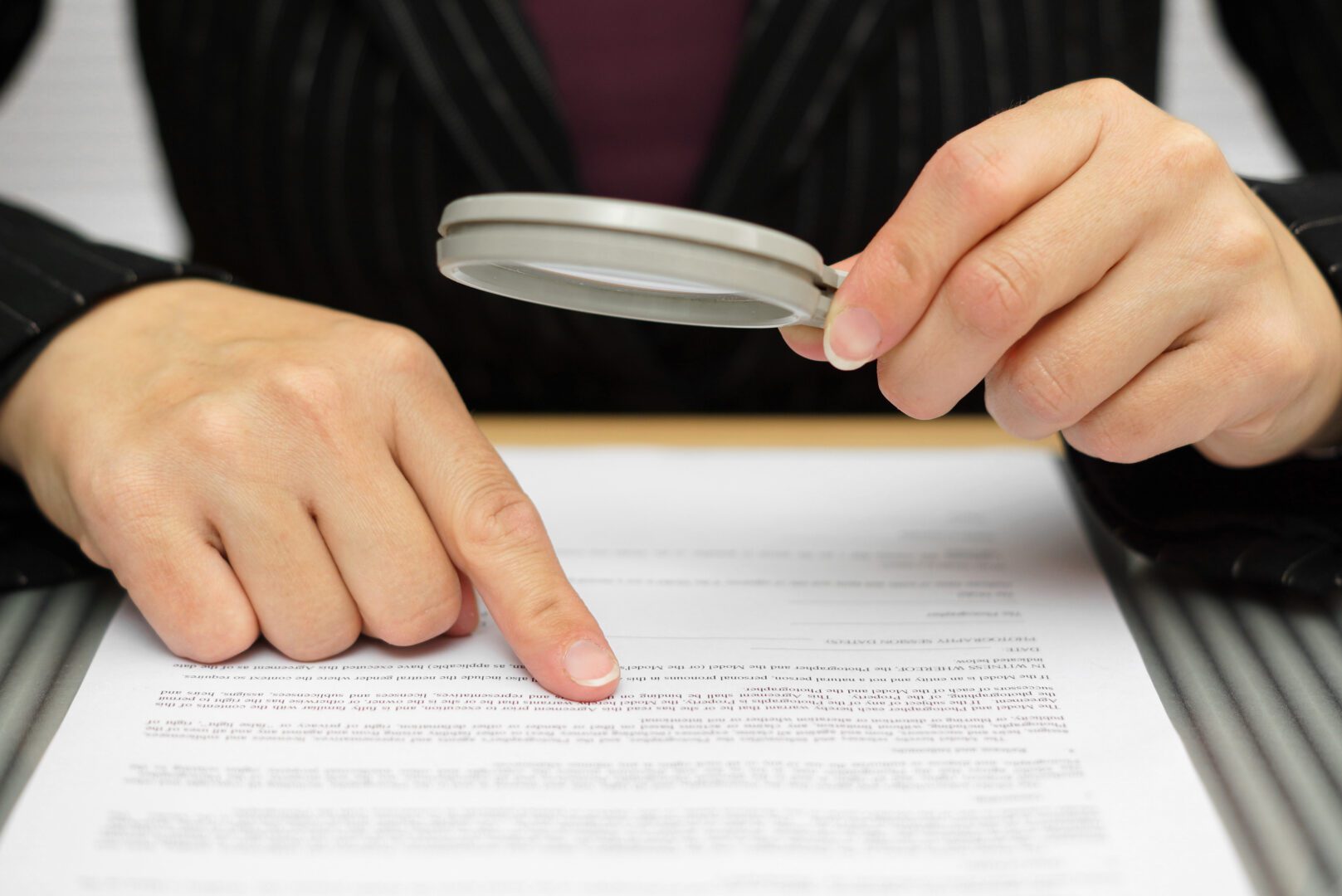 A person with a magnifying glass looking at papers